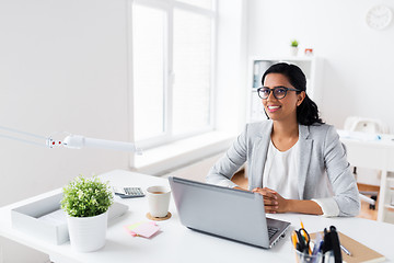 Image showing happy smiling businesswoman with laptop at office