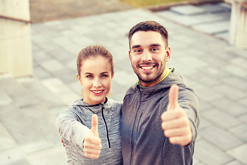 Image showing smiling couple showing thumbs up on city street