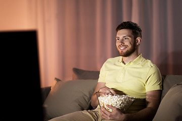 Image showing happy man with popcorn watching tv at night