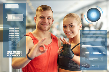 Image showing smiling man and woman showing ok hand sign in gym