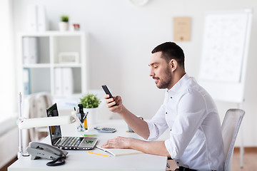 Image showing businessman with smartphone and notebook at office