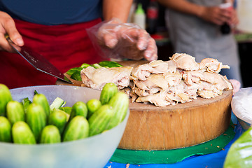 Image showing cook with poultry and cucumbers at street market