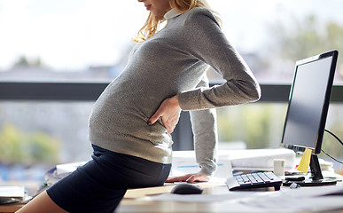 Image showing pregnant businesswoman sitting on table at office