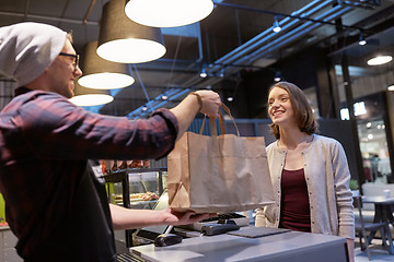 Image showing seller giving paper bag to customer at vegan cafe