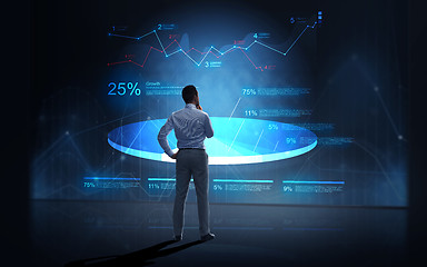 Image showing businessman looking at virtual charts over dark