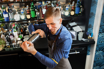 Image showing happy barman with shaker preparing cocktail at bar