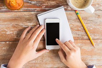 Image showing close up of male hands with smartphone on table