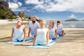 Image showing group of people making yoga exercises over beach