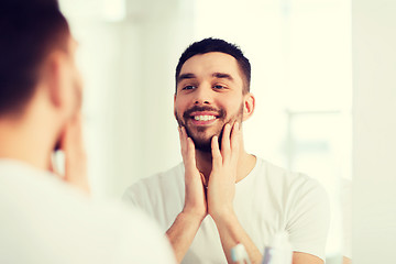 Image showing happy young man looking to mirror at home bathroom