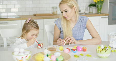 Image showing Mother looking at girl coloring eggs