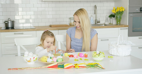 Image showing Loving mother and daughter coloring eggs