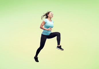 Image showing happy smiling sporty young woman jumping in air