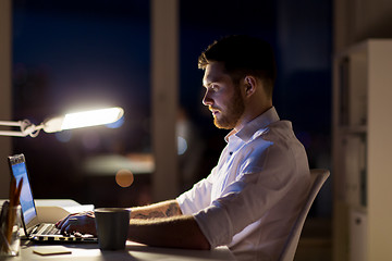 Image showing man with laptop and coffee working at night office