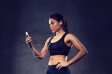 Image showing woman with smartphone and earphones in gym
