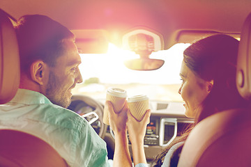 Image showing happy man and woman driving in car with coffee