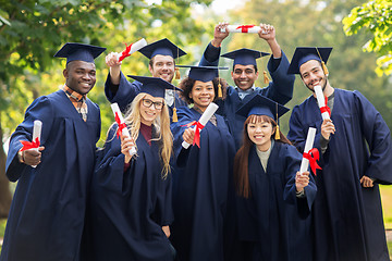 Image showing happy students in mortar boards with diplomas