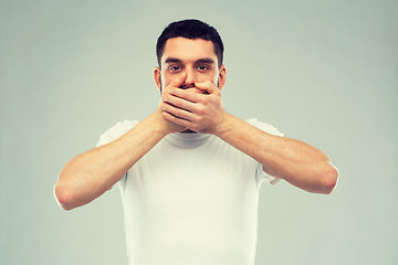 Image showing man in white t-shirt covering his mouth with hands