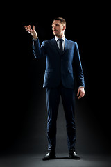 Image showing businessman in suit holding something invisible