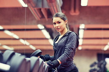 Image showing young woman choosing dumbbells in gym