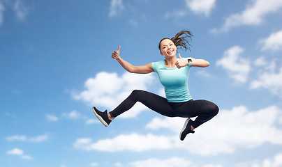 Image showing happy sporty young woman jumping in blue sky