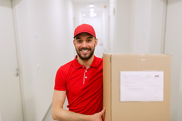 Image showing delivery man with parcel box in corridor