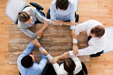 Image showing business people holding hands at office table