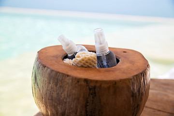 Image showing body lotion spray in coconut shell at beach spa