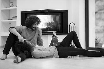 Image showing multiethnic couple used tablet computer on the floor