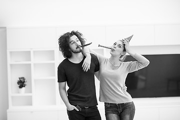 Image showing couple in party hats blowing in whistle