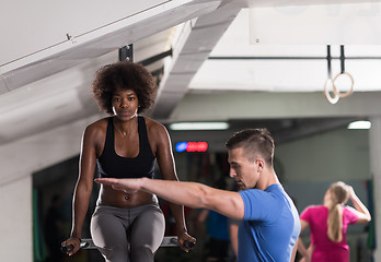 Image showing black woman doing parallel bars Exercise with trainer