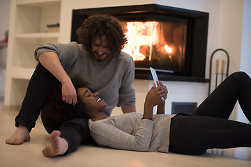 Image showing multiethnic couple using tablet computer on the floor