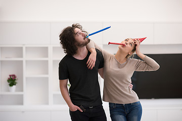 Image showing couple in party hats blowing in whistle