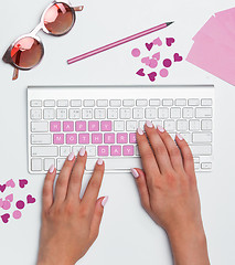 Image showing Office desk table with female hands, computer, supplies, flowers