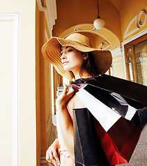 Image showing young pretty smiling woman in hat with bags on shopping at store