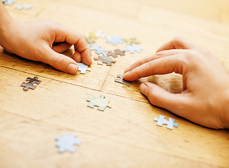 Image showing little kid playing with puzzles on wooden floor together with parent, lifestyle people concept, loving hands to each other 