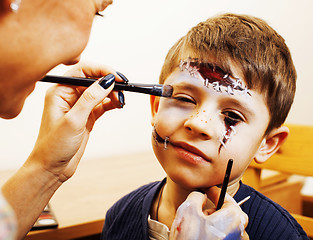 Image showing little cute child making facepaint on birthday party, zombie Apocalypse facepainting, halloween preparing concept at home