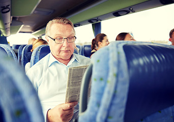 Image showing happy senior man reading newspaper in travel bus