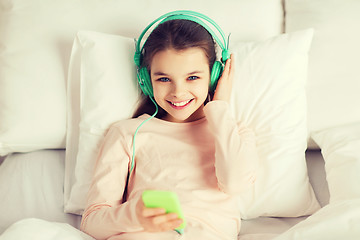 Image showing happy girl lying in bed with smartphone at home