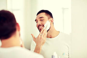 Image showing happy man applying shaving foam at bathroom mirror