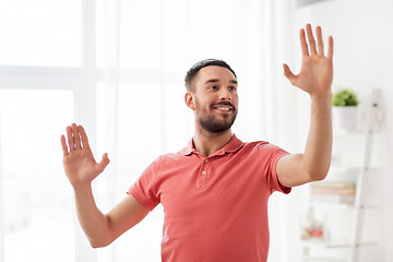 Image showing happy man touching something imaginary at home