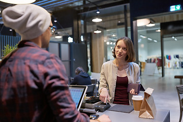 Image showing happy woman paying for purchases at cafe