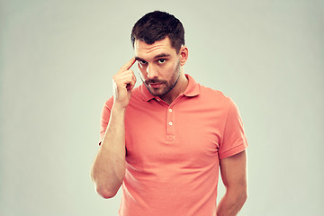 Image showing man with finger at temple over gray background