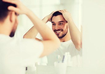 Image showing happy young man looking to mirror at home bathroom