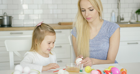 Image showing Cheerful girl painting eggs with mother