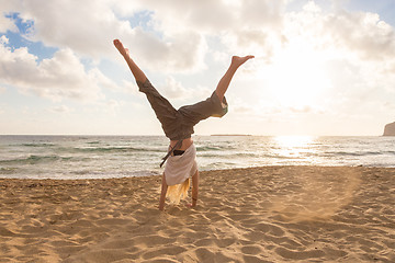 Image showing Free Happy Woman Turning Cartwheel Enjoying Sunset on Sandy Beach.