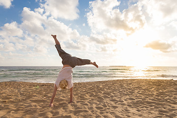 Image showing Free Happy Woman Turning Cartwheel Enjoying Sunset on Sandy Beach.