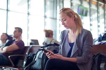 Image showing Female traveler using cell phone while waiting on airport.