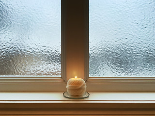 Image showing Candle on windowsill of a frosted window