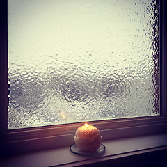 Image showing Frosted winter window and burning candle