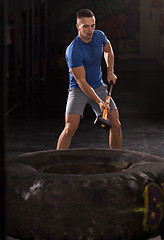 Image showing man workout with hammer and tractor tire